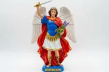Poderosa Oración a San Miguel Arcángel para los enfermos: Estatua de San Miguel Arcángel con espada levantada, alas extendidas y ramos de lavanda y flores en mano, sobre base que dice “Para los enfermos”.